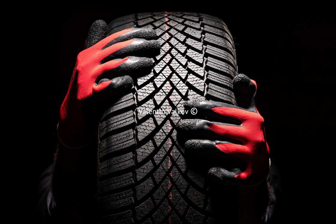 "Car tire service and hands of mechanic holding new tyre on black" stock image