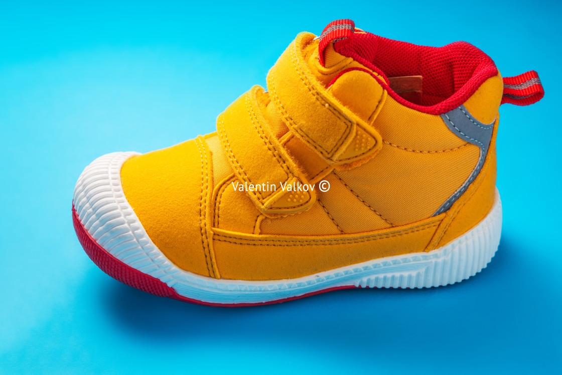 "Yellow baby shoes. Kids sport sneakers isolated on blue background" stock image