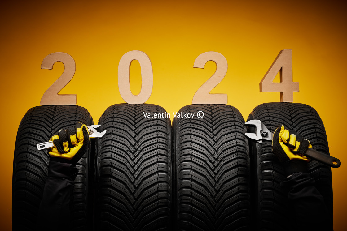 "Winter car tires servic, hands of mechanic with wrench screwdriver and text 2024 happy new year background" stock image