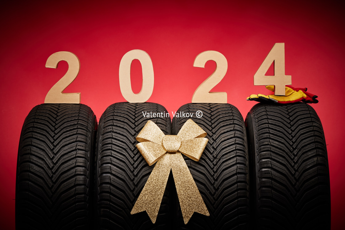 "Car tires, new tyres, winter wheels gold bow ribbon present, text 2024 happy new year christmas background" stock image