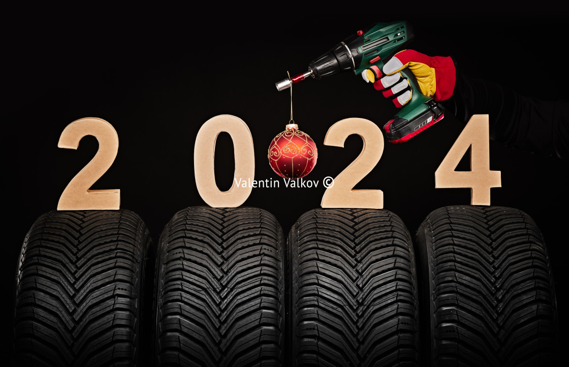 "Winter car tires, big wheels service and hand of mechanic man with wrench and christmas ball, new year 2024 black background" stock image