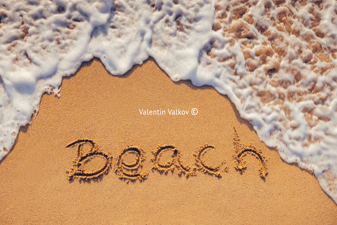 "Beach handwritten text on the sand of tropical island shore and ocean wave as nature background" stock image