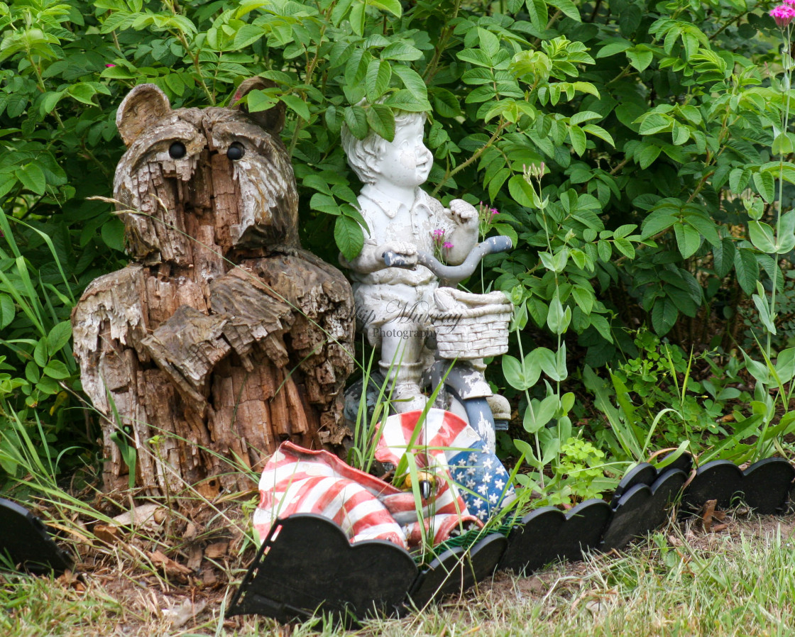 "Bear sculpture next to child on tricycle" stock image