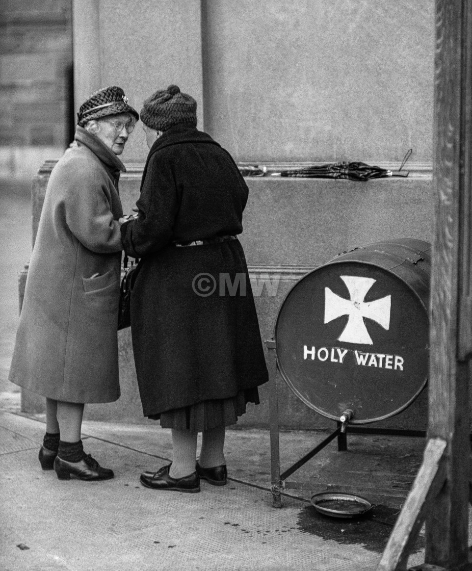 "Two old ladies chat while collecting holy water from a barrel be" stock image