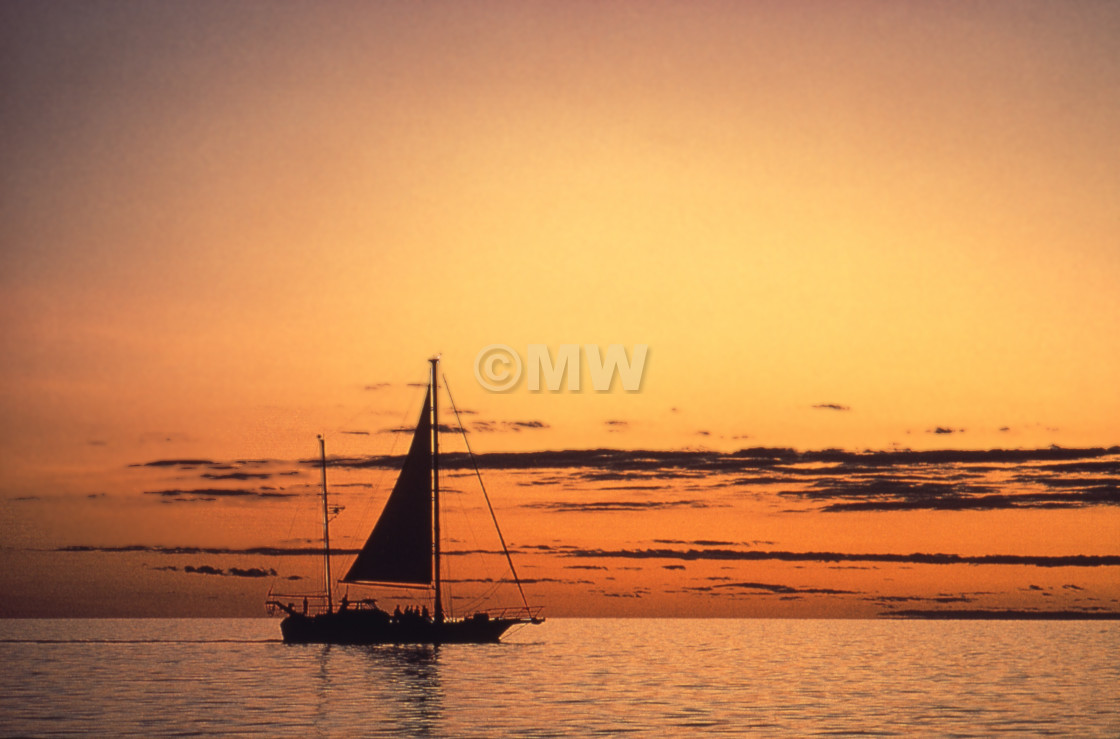 "Yacht silhouette on orange sea with setting sun" stock image