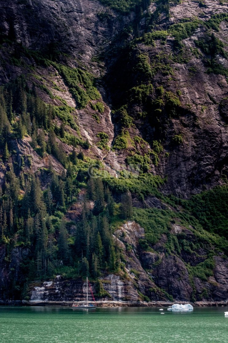 "Yacht dwarfed by mountain wall" stock image