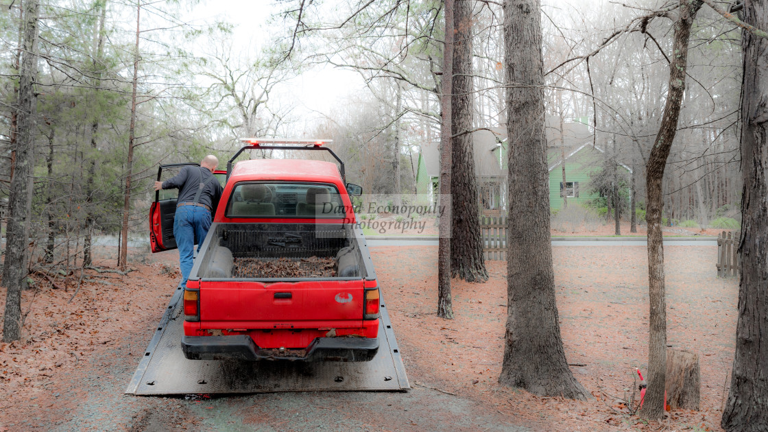 "Red pickup truck being loaded on red tilt bed tow truck to be hauled away" stock image