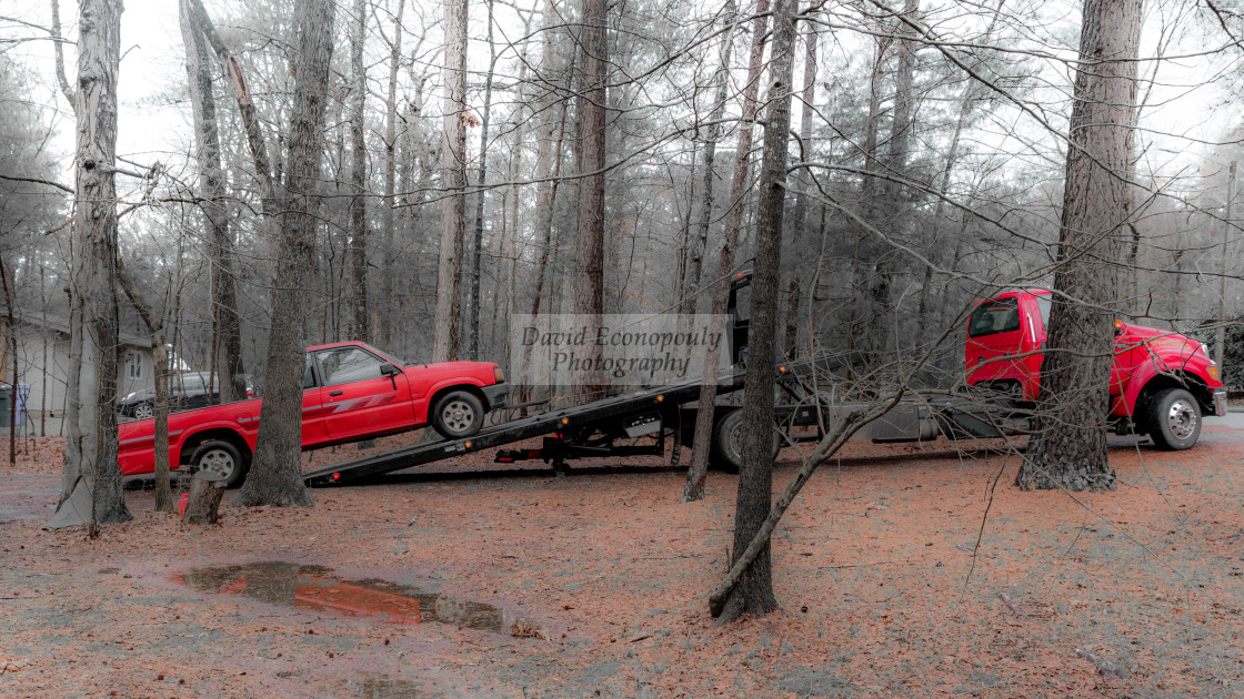 "Red pickup truck being loaded on red tilt bed tow truck to be hauled away" stock image