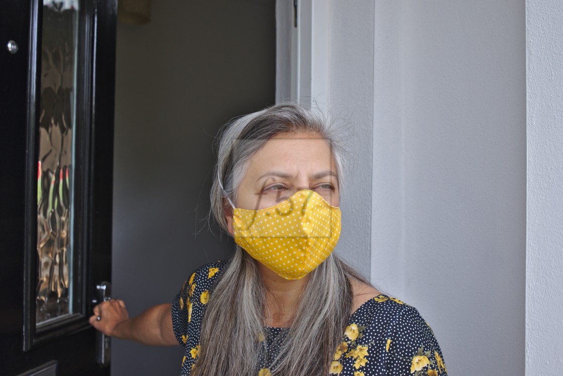 "A woman wears a face mask covering as coronavirus lockdown eases." stock image