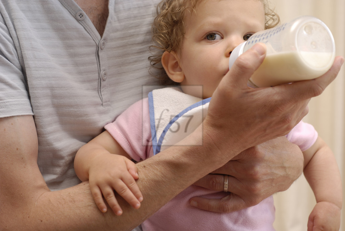 "Dad giving baby daughter a bottle of milk" stock image