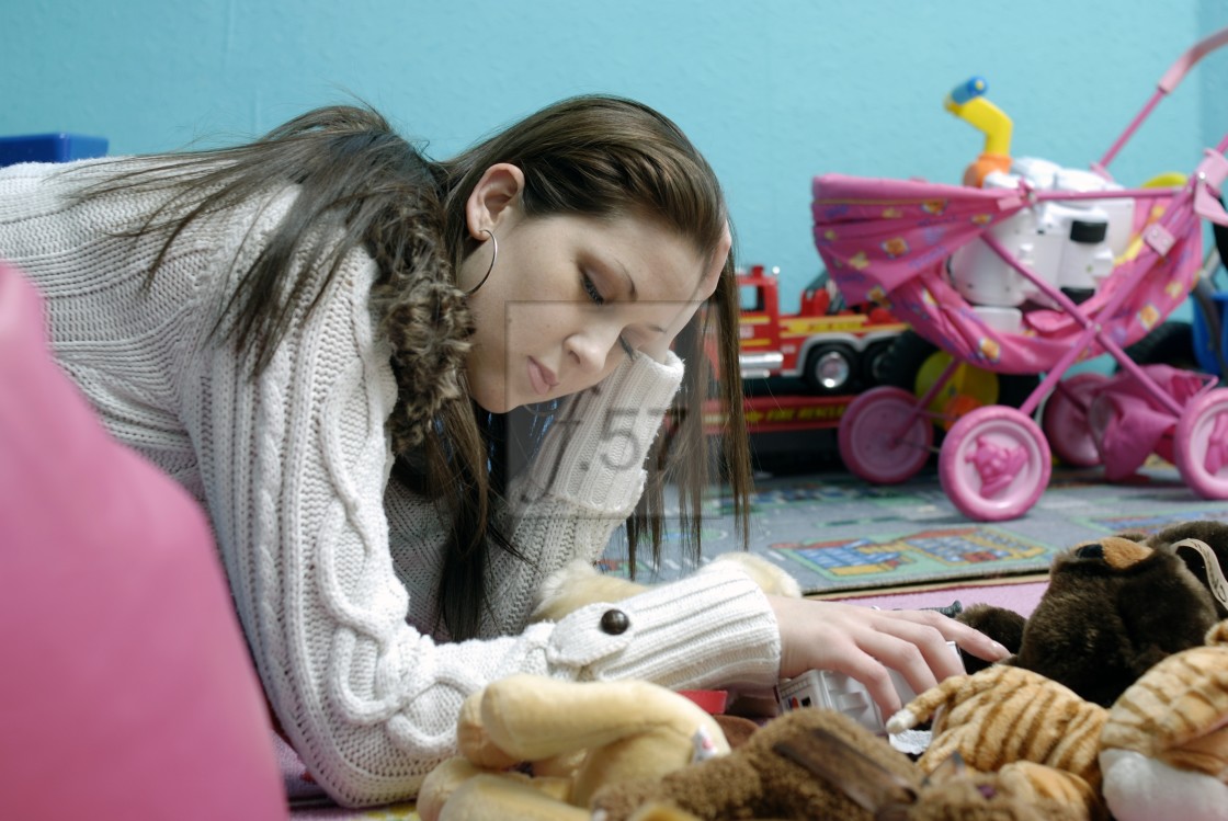 "A tired young mum resting for a moment before tidying her children's messy playroom." stock image