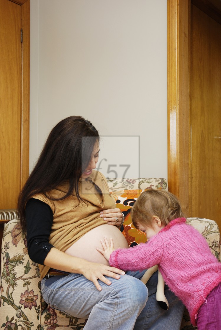 "A mother pregnant with her second baby shares her excitement with her twenty month old daughter." stock image