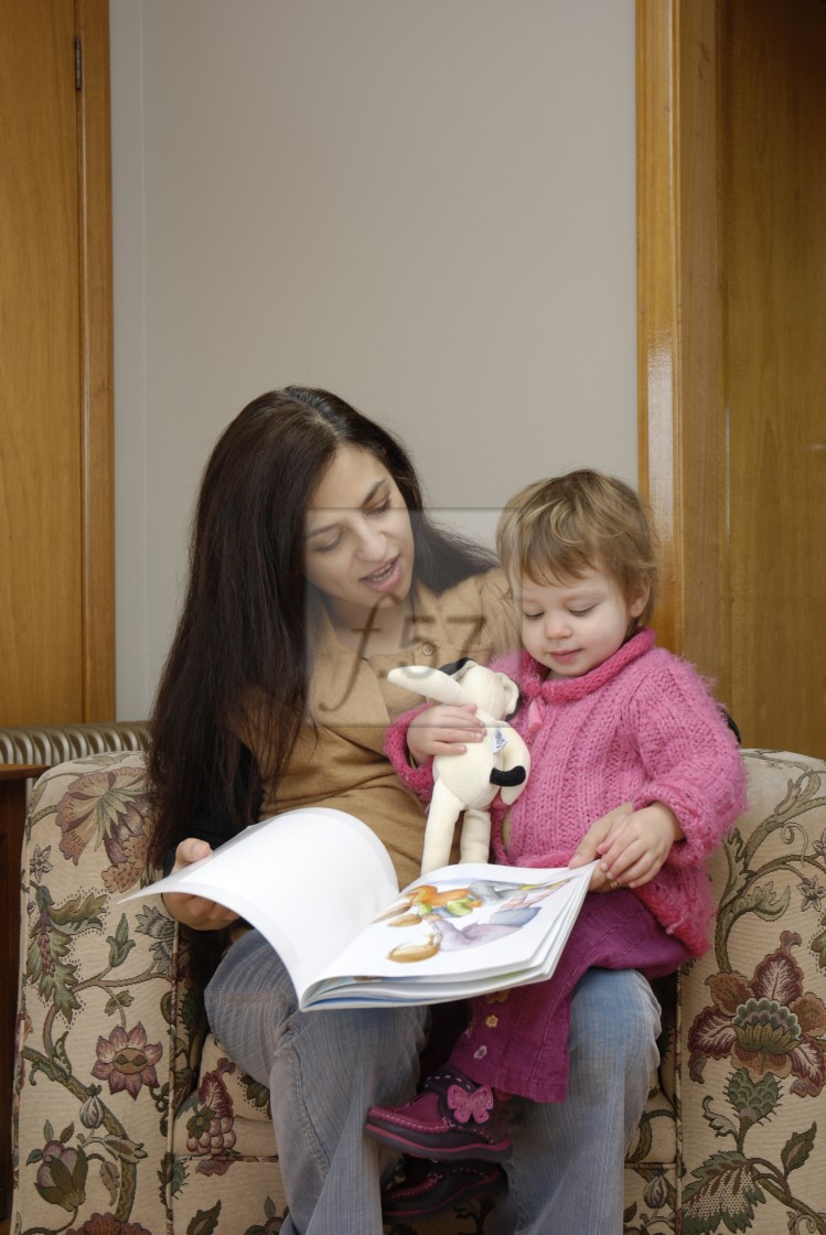 "A mother reading a book with her twenty month old daughter." stock image