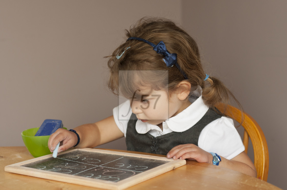 "Four year old girl in school uniform practising writing on a small chalk board." by HD57 lifestyle stock photography - $29.40 "Four year old girl in school uniform practising writing on a small chalk board." stock image