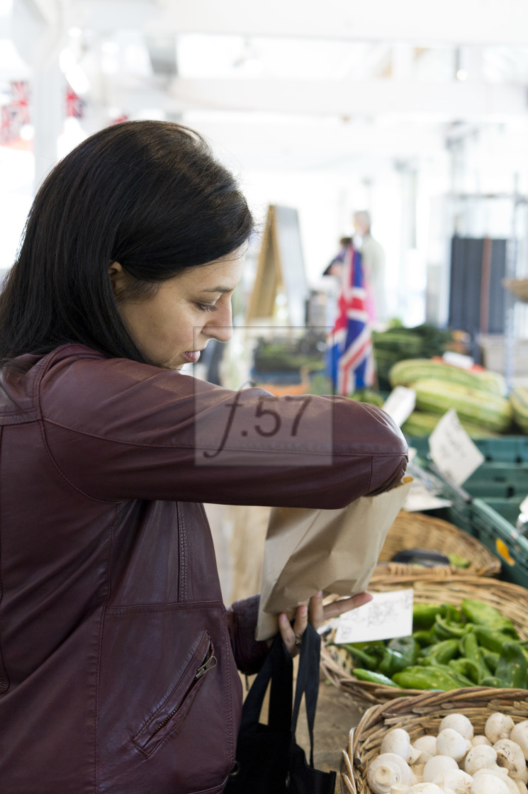 "Woman buying vegetables in a local market. Tiverton Devon UK." stock image