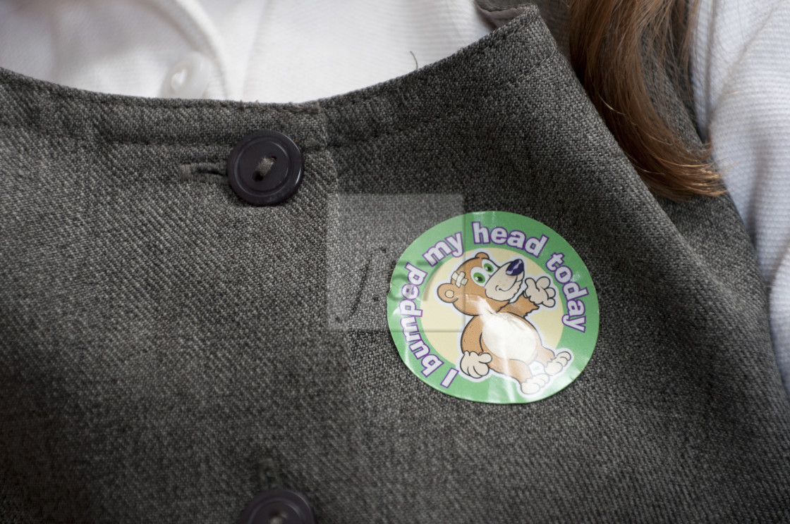 "Primary school pupil with bumped head sticker on her uniform." stock image