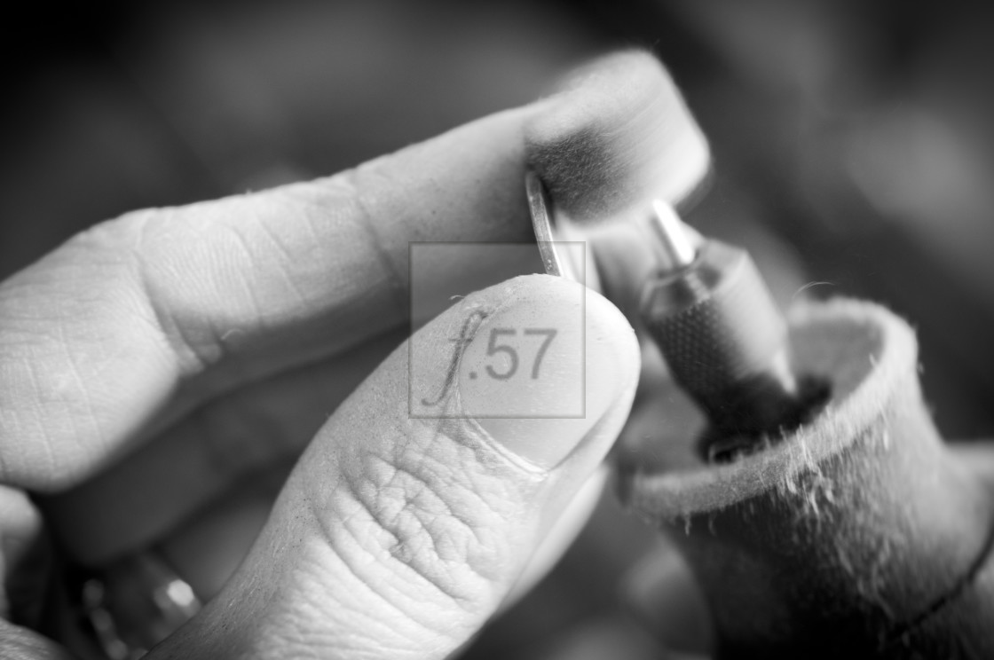 "Jewelery maker polishing work. Close up of artisan hands at work." stock image