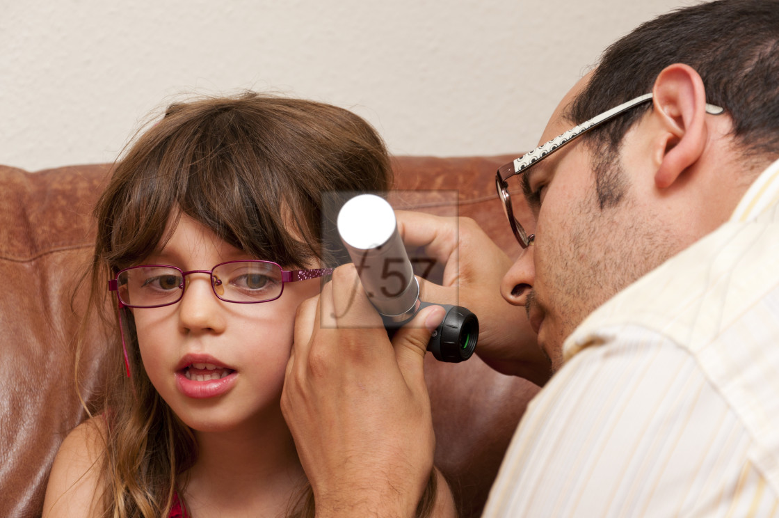 "Doctor on a home visit examining a child with a otoscope." stock image