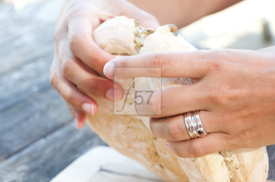 "Woman's hands breaking bread loaf to share food. Australian damper bread." stock image