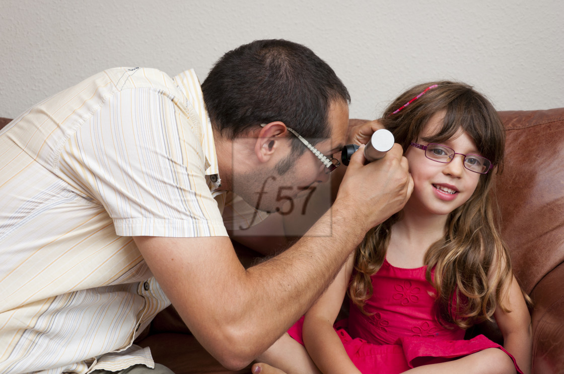 "Doctor on a home visit examining a child with a otoscope." stock image