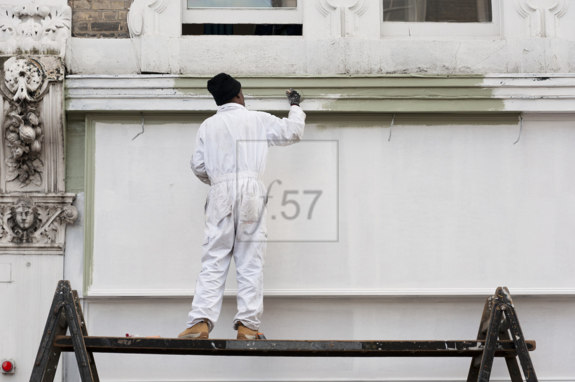 "Painter and decorator working at height on the exterior of a building." stock image