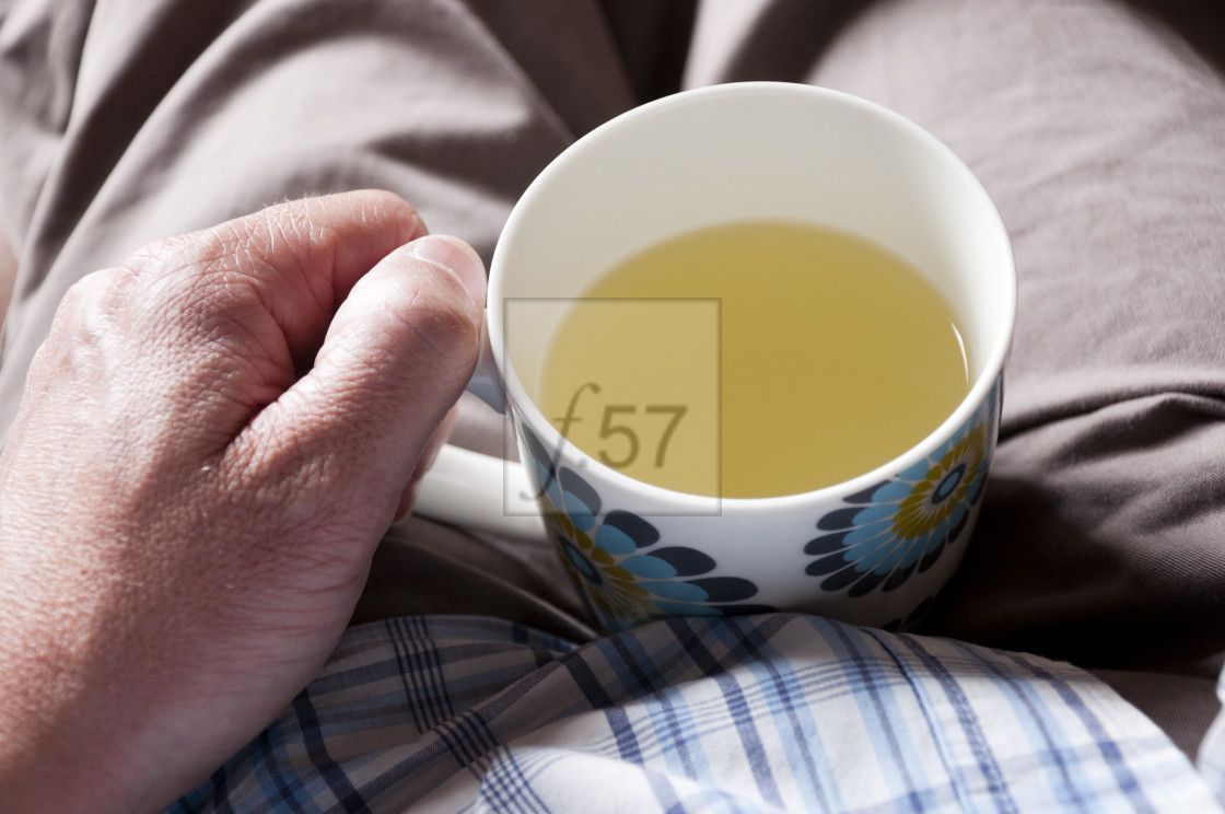 "Man suffering with cold holding mug of lemsip in his lap." stock image