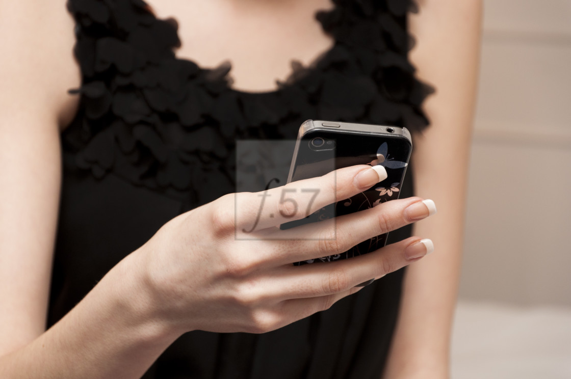 "Woman in little black dress texting on mobile phone" stock image