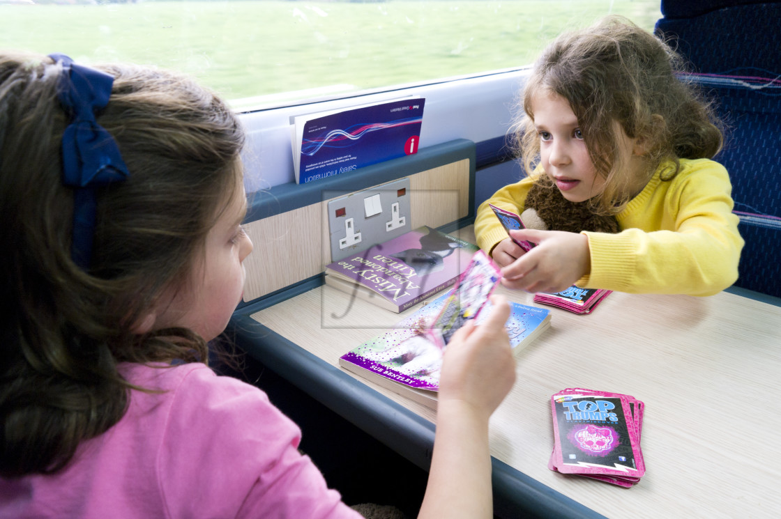 "children playing top trumps card game during a train journey." stock image