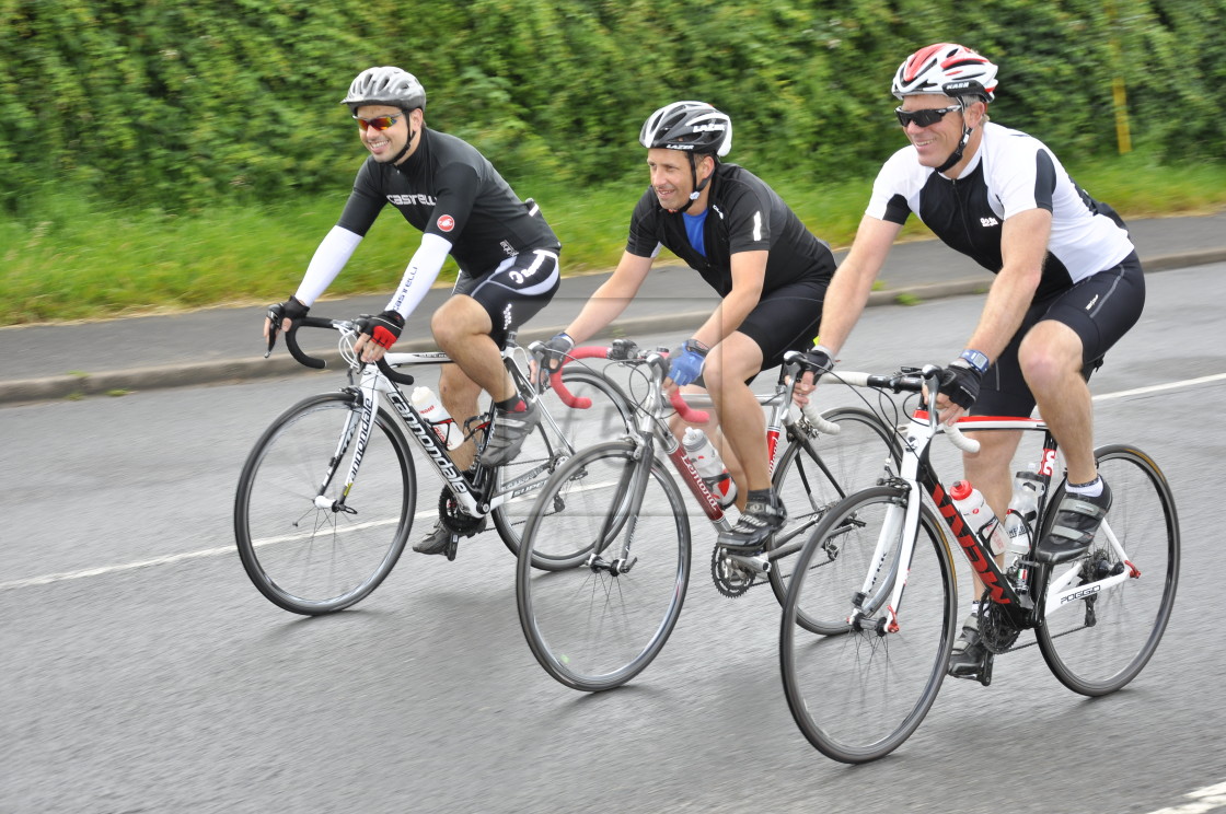 "Three cyclists riding road bikes" stock image