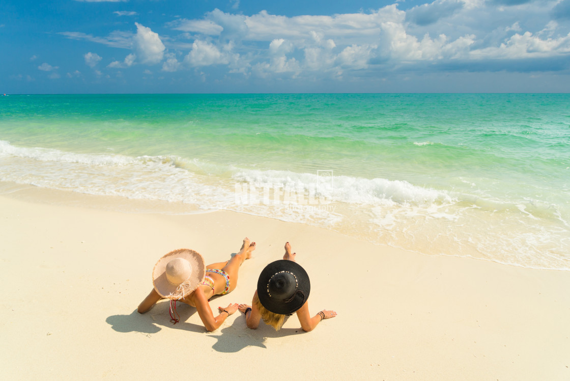 "Sexy bikini body of two women enjoy the sea by laying down on sand of beach..." stock image