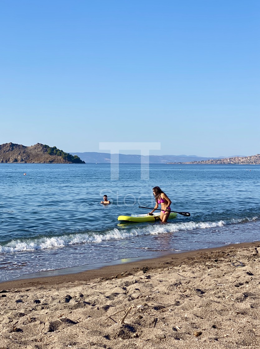 "Young woman wearing a pink bikini in the sea with sup board by the beach." by TTStock - $7.54 "Young woman wearing a pink bikini in the sea with sup board by the beach." stock image
