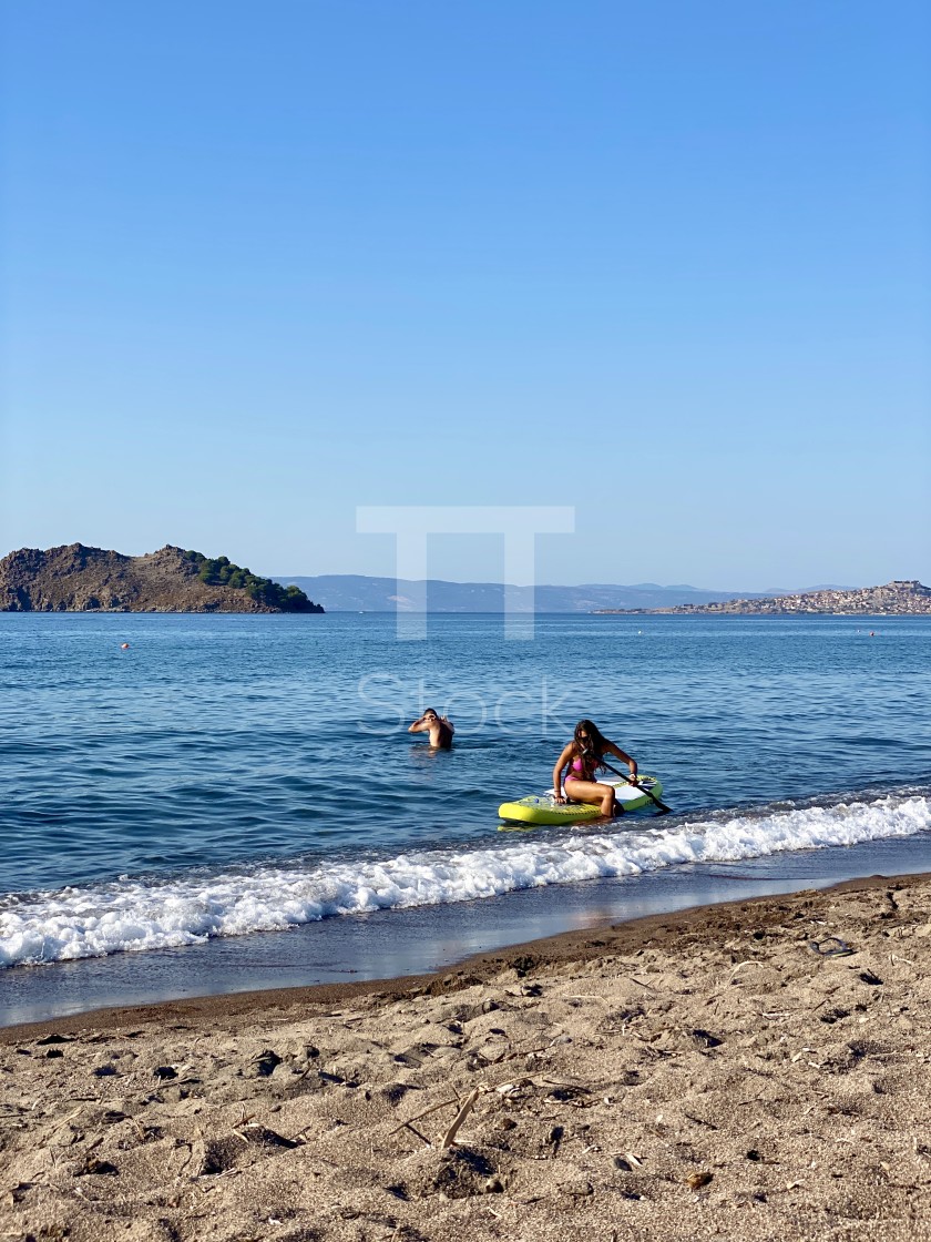 "Young woman wearing a pink bikini getting off a sup board by the beach." by TTStock - $7.54 "Young woman wearing a pink bikini getting off a sup board by the beach." stock image