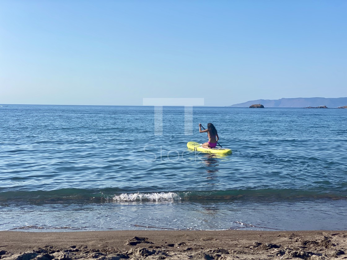 "Young woman wearing a pink bikini kneeling on a yellow sup board at sea." by TTStock - $7.54 "Young woman wearing a pink bikini kneeling on a yellow sup board at sea." stock image