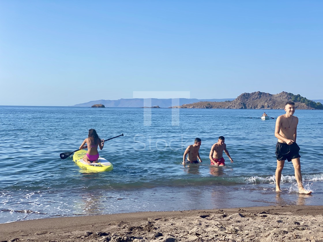 "Young woman wearing a pink bikini on the beach kneeling on sup board, youths walk out the sea." by TTStock - $7.54 "Young woman wearing a pink bikini on the beach kneeling on sup board, youths walk out the sea." stock image