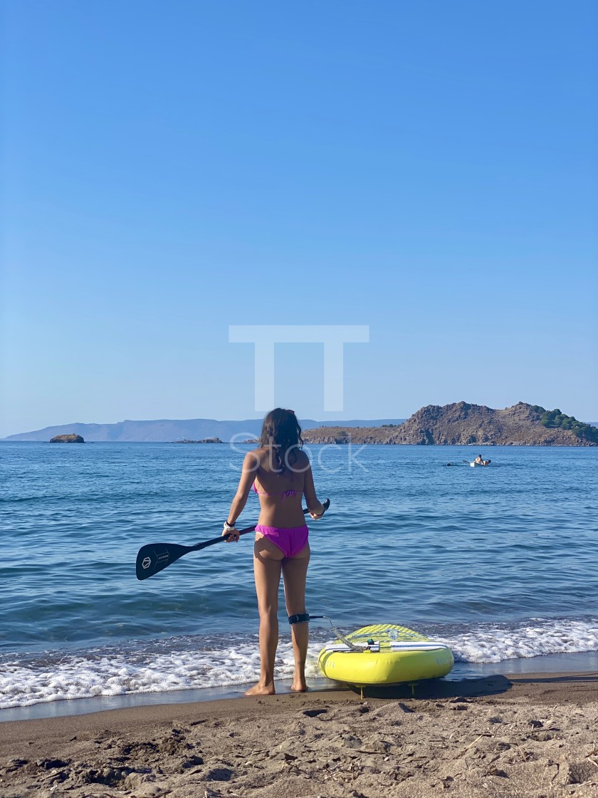 "Young woman wearing a pink bikini standing on the beach with a yellow sup board attached." by TTStock - $7.54 "Young woman wearing a pink bikini standing on the beach with a yellow sup board attached." stock image