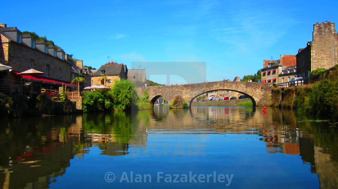 "Reflection of bridge and village on river" stock image