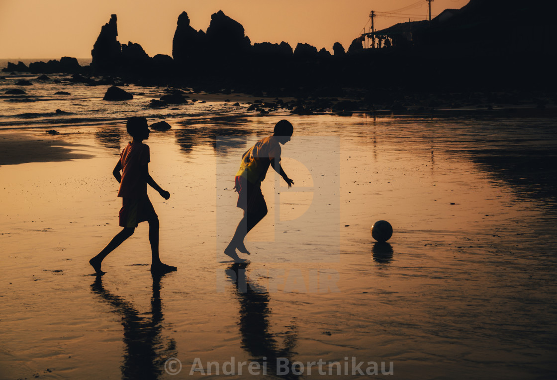 "Two boys play soccer on beach in dusk, Goa, India" stock image