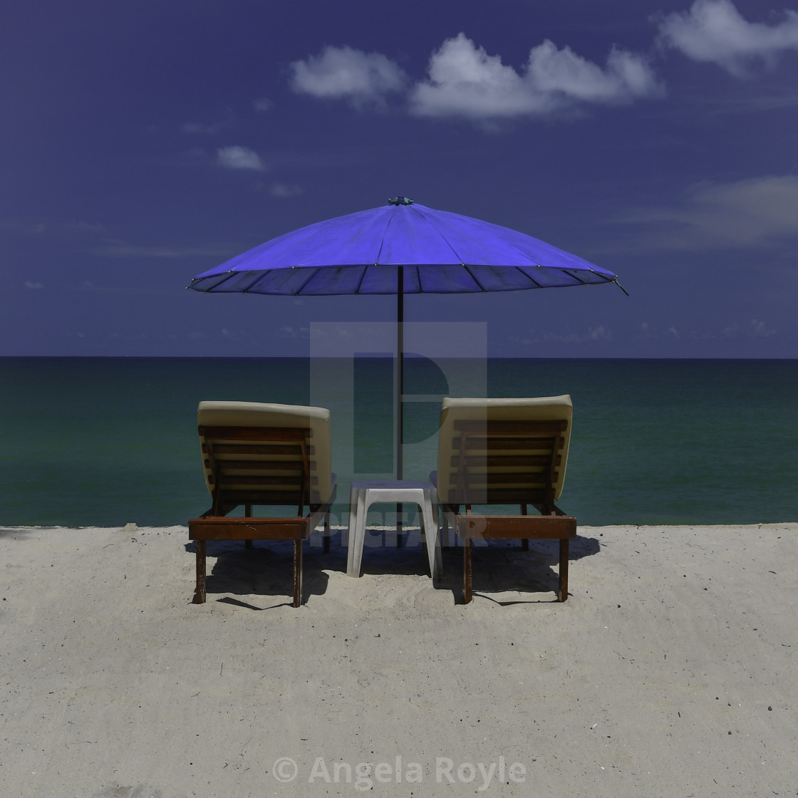 "White sand beach, sunloungers and blue parasol" stock image