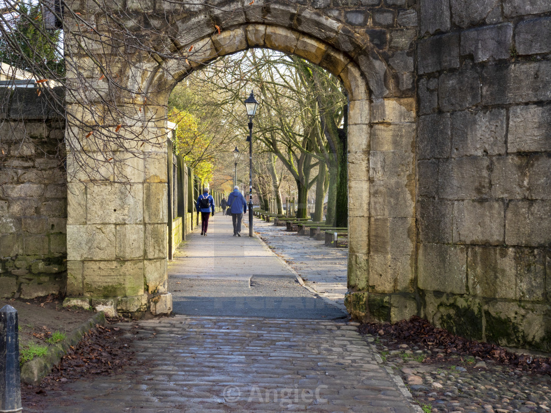 "View through and arch to a tree lined riverside walk in York, England" stock image