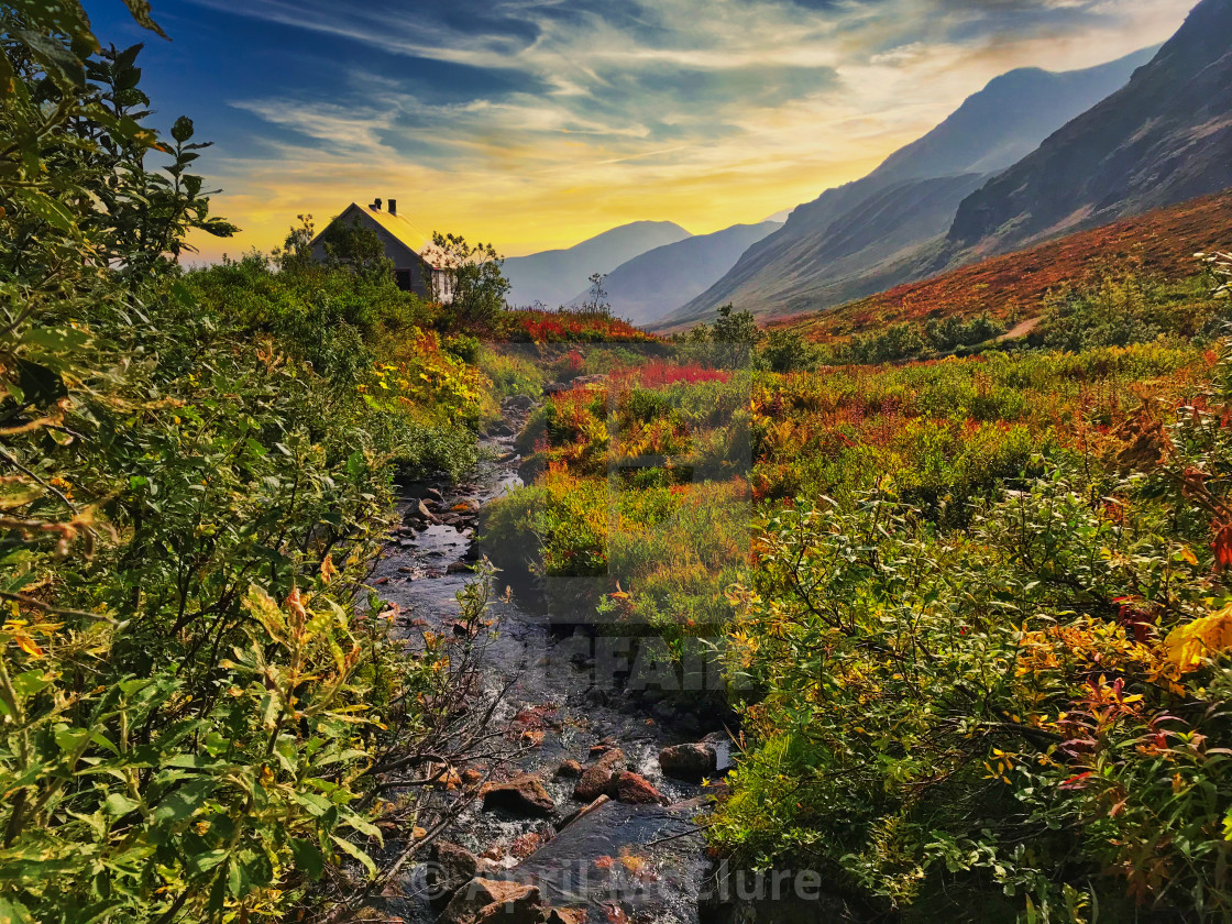 "Alaska Mountain Stream flowing towards a rustic cabin" stock image