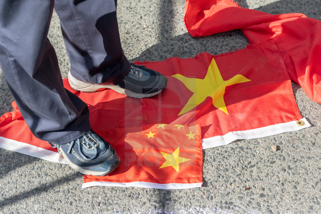 "Man Stepping On Ripped-up Chinese Flags" by Beth Baisch - $12.33 "Man Stepping On Ripped-up Chinese Flags" stock image