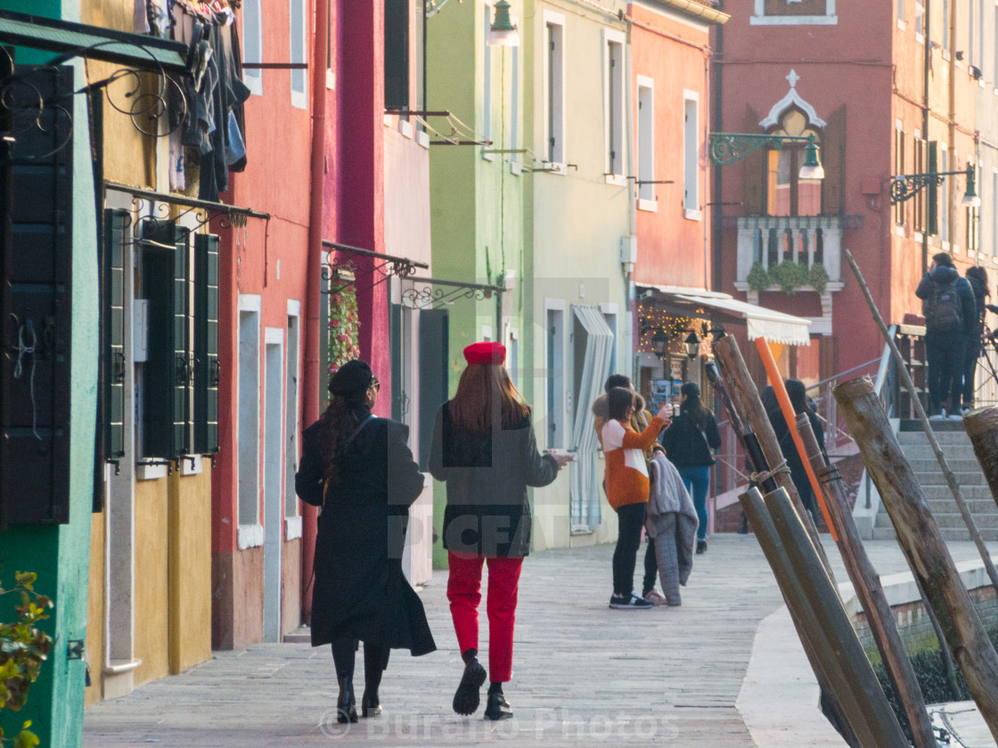 "Two friends on a walk in Burano, among the colorful houses." stock image