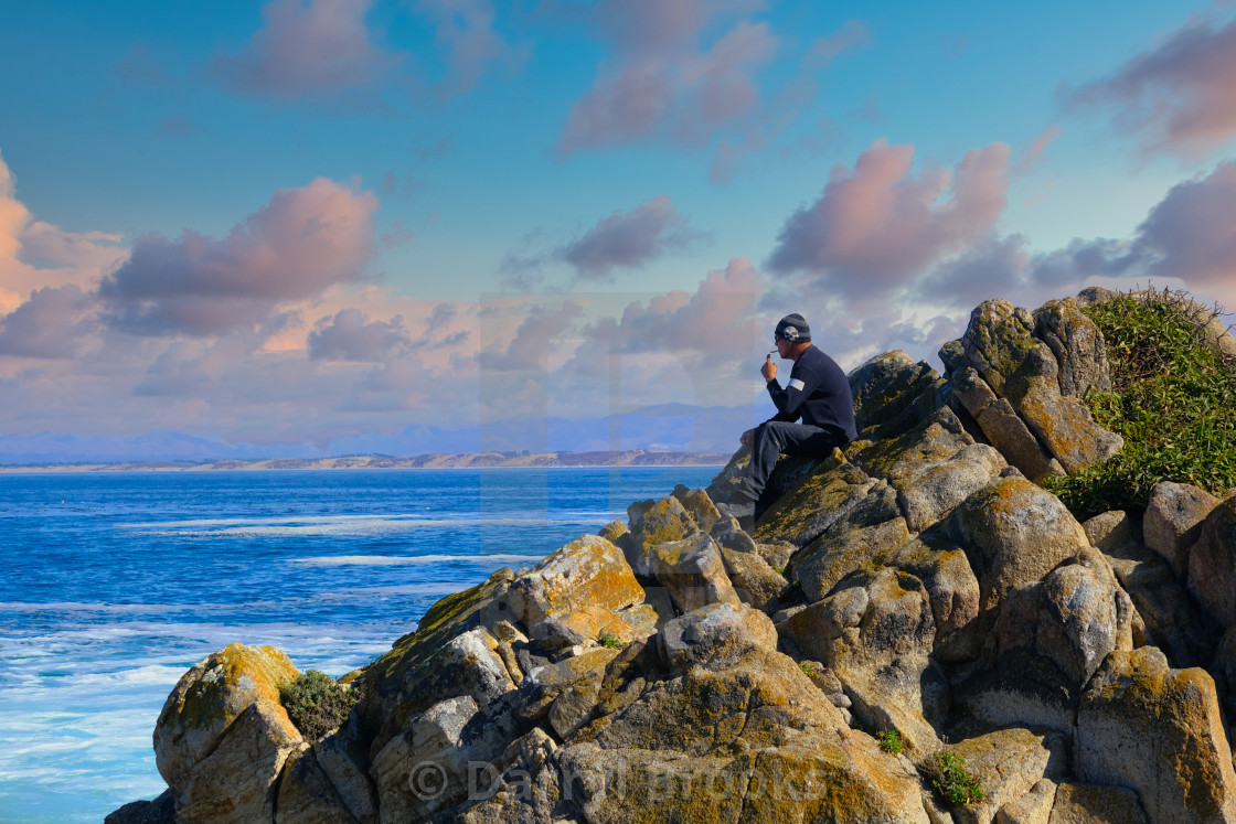 "Man Sitting on Pacific Rocks" stock image