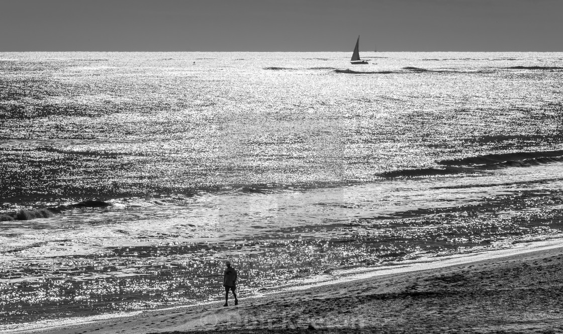 "Beach scene in black and white -sailboat and beach walker" by Don Keeton - £5.00 "Beach scene in black and white -sailboat and beach walker" stock image