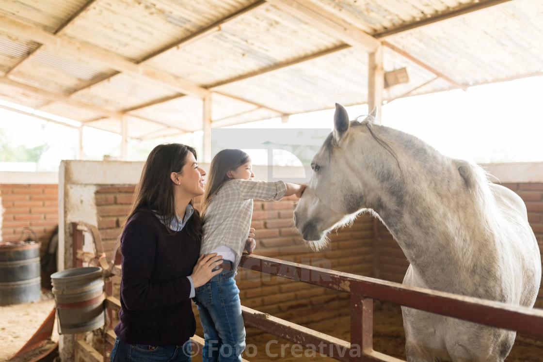 "Woman With Daughter Touching Horse In Barn" by Foto Creativa - £3.80 "Woman With Daughter Touching Horse In Barn" stock image