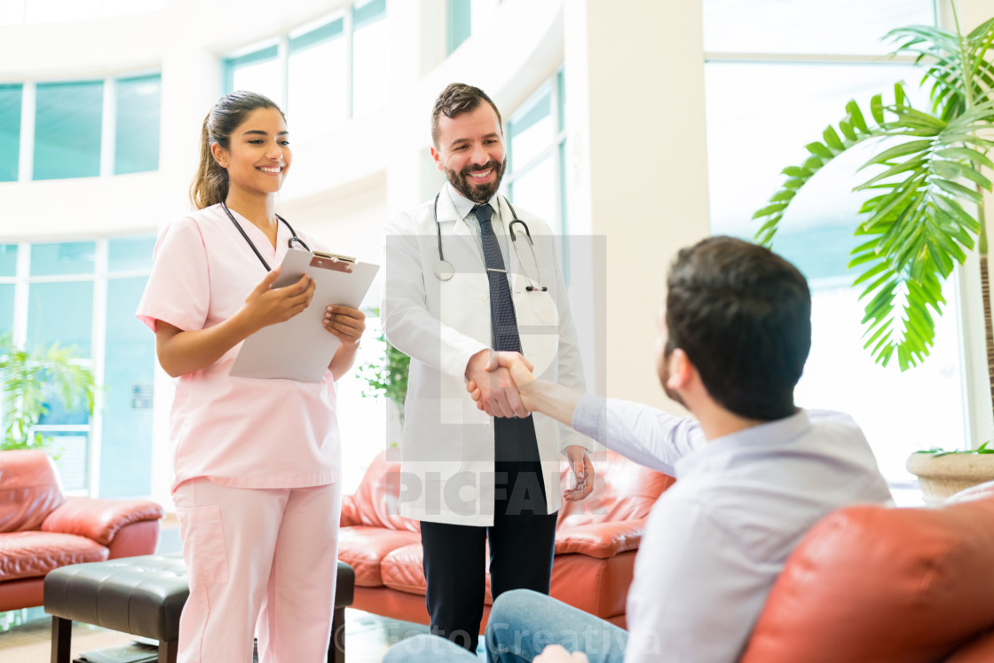 "Healthcare Workers Greeting Man Waiting At Hospital" by Foto Creativa - £3.80 "Healthcare Workers Greeting Man Waiting At Hospital" stock image