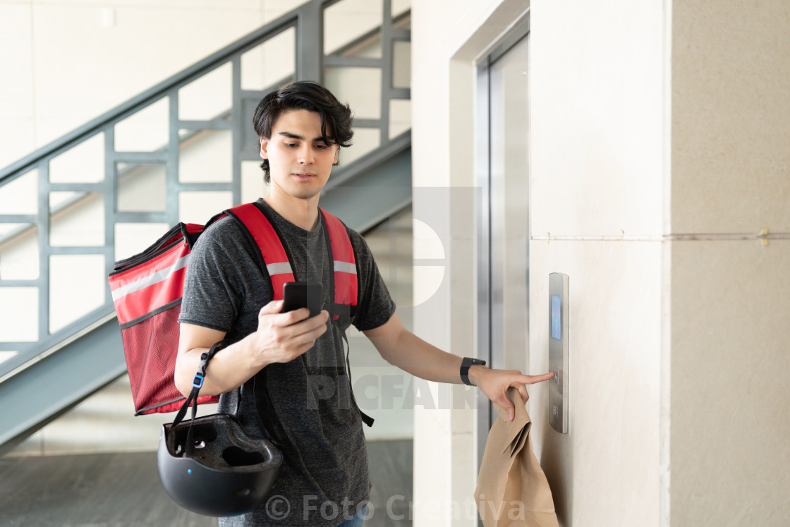 "Delivery Man With Parcel Waiting For Elevator In Apartment" by Foto Creativa - £3.80 "Delivery Man With Parcel Waiting For Elevator In Apartment" stock image