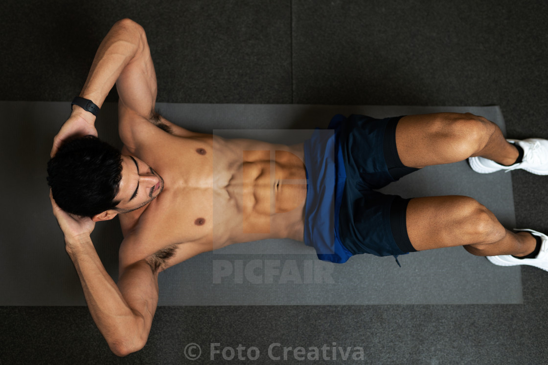 "Hispanic man without a shirt doing sit up exercises" by Foto Creativa - £3.80 "Hispanic man without a shirt doing sit up exercises" stock image