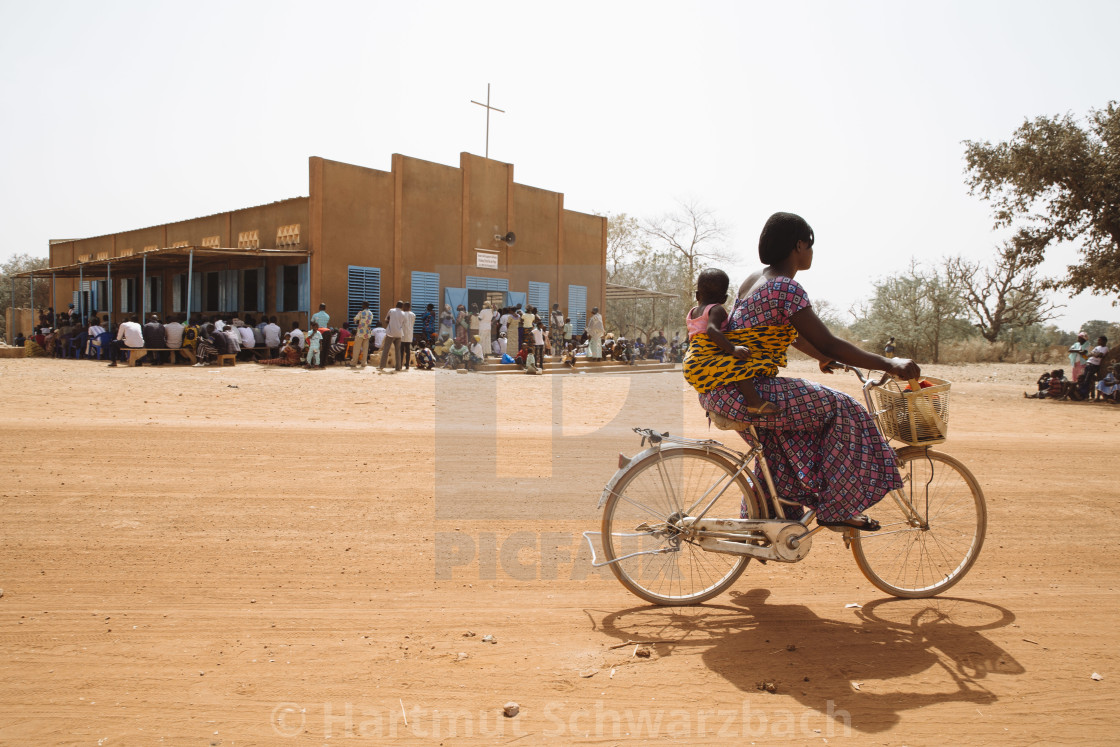 "Catholic Mass on Sunday in Burkina Faso, Woman on bicycle" stock image