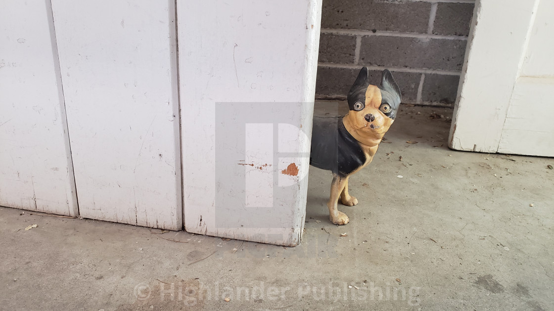 "Dog statue looks around corner" stock image